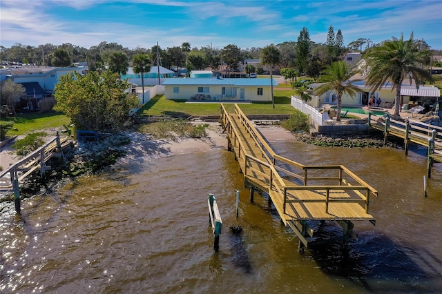 view of dock with a lawn and a water view