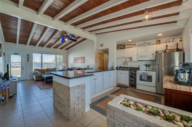 kitchen with kitchen peninsula, white cabinetry, lofted ceiling with beams, and white appliances