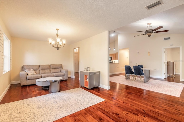 living room featuring ceiling fan with notable chandelier, a textured ceiling, vaulted ceiling, and dark wood-type flooring