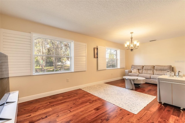 living room with a textured ceiling, dark hardwood / wood-style floors, a chandelier, and plenty of natural light