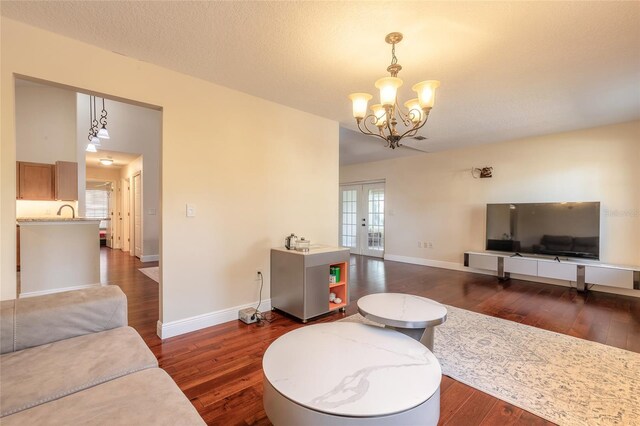 living room with a wealth of natural light, french doors, a chandelier, and dark hardwood / wood-style floors