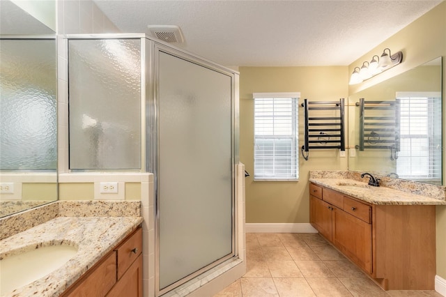 bathroom featuring an enclosed shower, vanity, a textured ceiling, and tile patterned floors