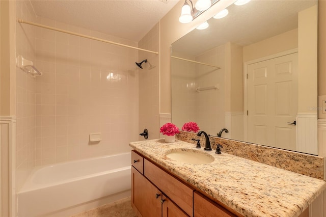 bathroom featuring a textured ceiling,  shower combination, and vanity