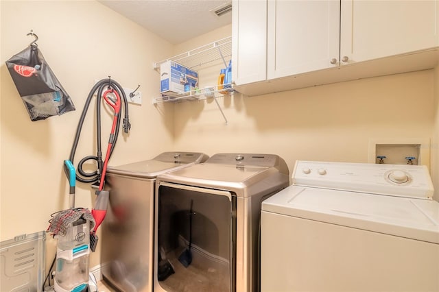 clothes washing area featuring cabinets and independent washer and dryer