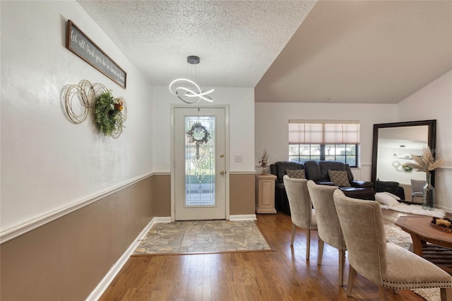 foyer entrance with a textured ceiling, hardwood / wood-style flooring, and a notable chandelier