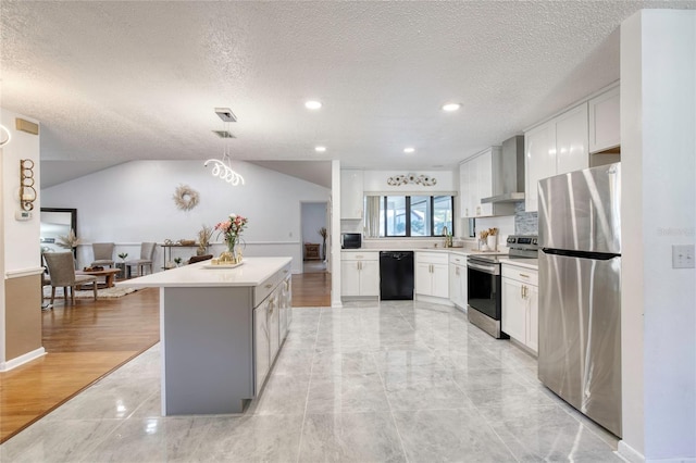 kitchen with white cabinets, a kitchen island, wall chimney range hood, and black appliances