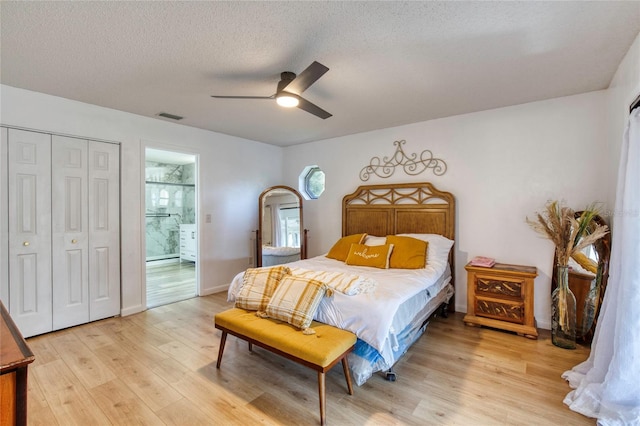 bedroom with a textured ceiling, connected bathroom, light hardwood / wood-style floors, and ceiling fan