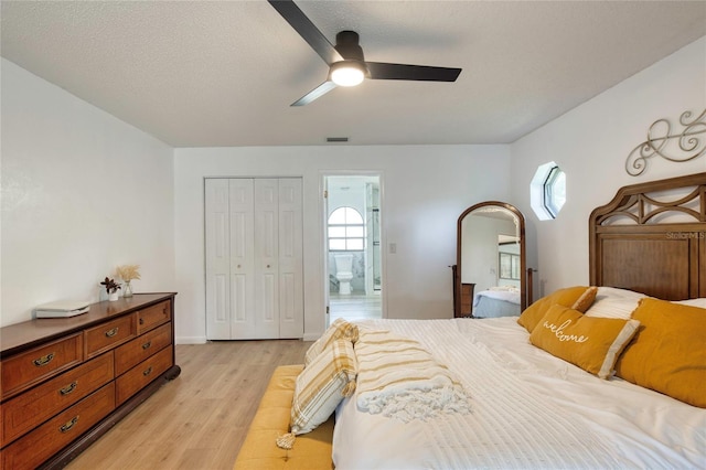 bedroom featuring ensuite bath, ceiling fan, a textured ceiling, a closet, and light wood-type flooring