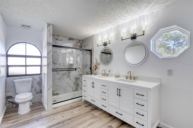 bathroom with toilet, wood-type flooring, a shower with door, and vanity