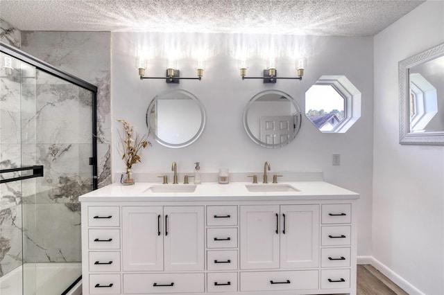 bathroom featuring hardwood / wood-style flooring, vanity, combined bath / shower with glass door, and a textured ceiling