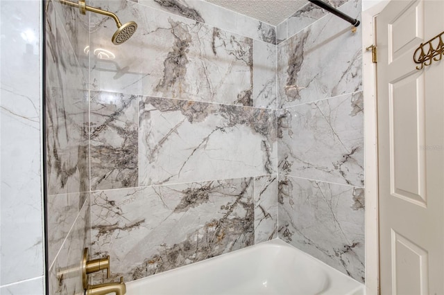 bathroom with a textured ceiling and tiled shower / bath combo