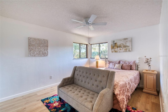 bedroom featuring ceiling fan, a textured ceiling, and light wood-type flooring