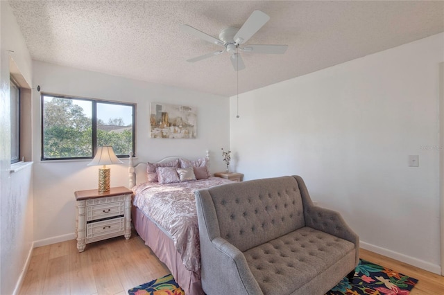 bedroom with a textured ceiling, light hardwood / wood-style floors, and ceiling fan