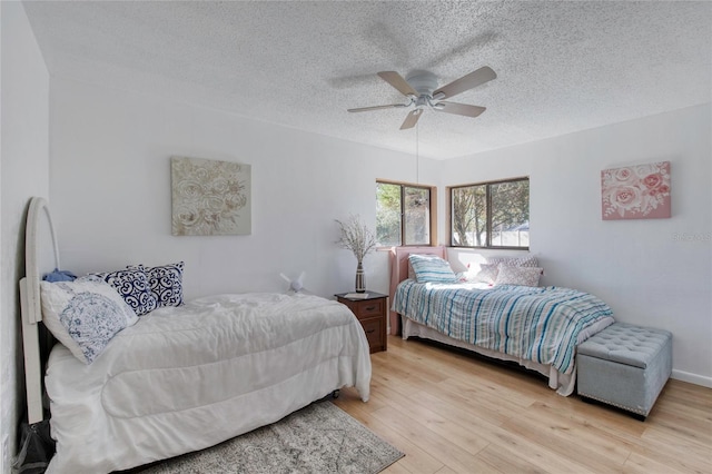 bedroom with ceiling fan, light hardwood / wood-style flooring, and a textured ceiling