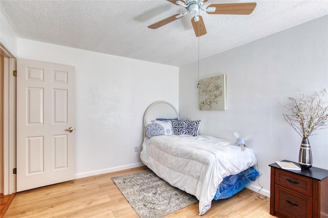 bedroom with a textured ceiling, light hardwood / wood-style flooring, and ceiling fan