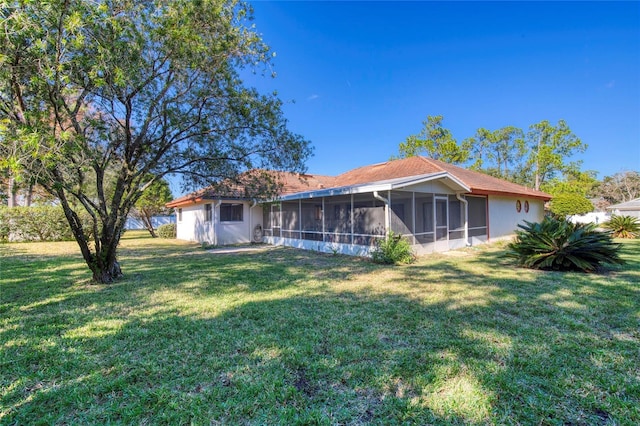 rear view of house featuring a yard and a sunroom