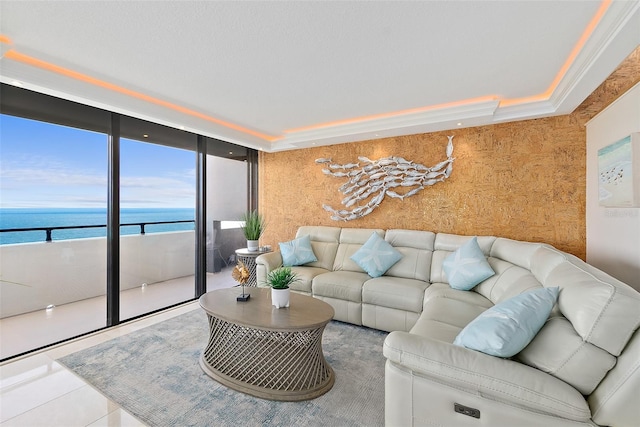 tiled living room featuring a raised ceiling, floor to ceiling windows, a water view, and ornamental molding