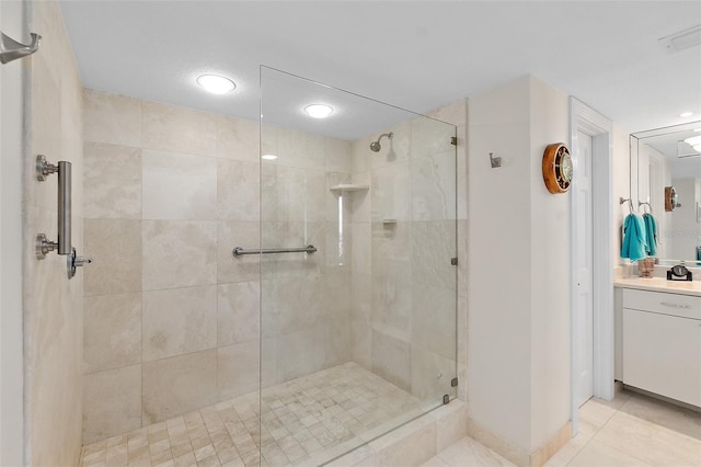 bathroom featuring tile patterned flooring, vanity, and a tile shower