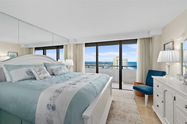 bedroom with expansive windows, a water view, and access to outside