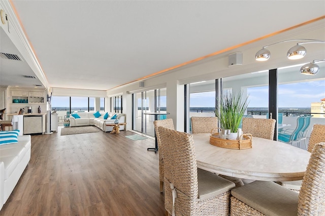 dining area featuring hardwood / wood-style floors, a healthy amount of sunlight, a water view, and ornamental molding