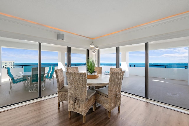 dining area with a water view, hardwood / wood-style flooring, and ornamental molding