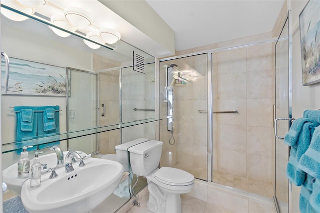 bathroom with tile patterned floors, sink, a shower with shower door, and toilet