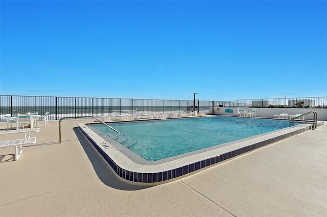 view of pool featuring a water view and a patio area