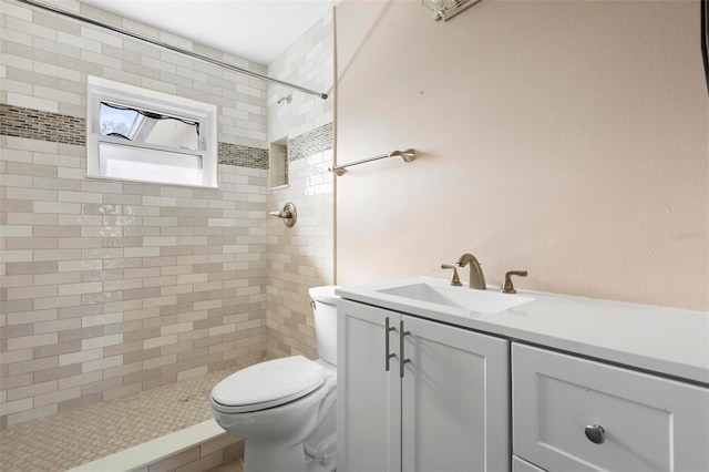 bathroom with a tile shower, vanity, and toilet