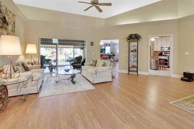 living room with ceiling fan, high vaulted ceiling, and light hardwood / wood-style floors