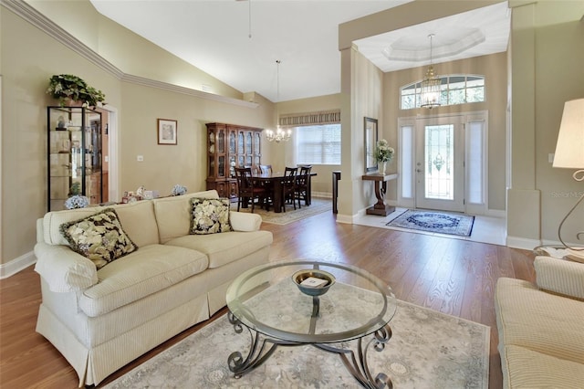 living room featuring a healthy amount of sunlight, light wood-type flooring, a towering ceiling, and a chandelier