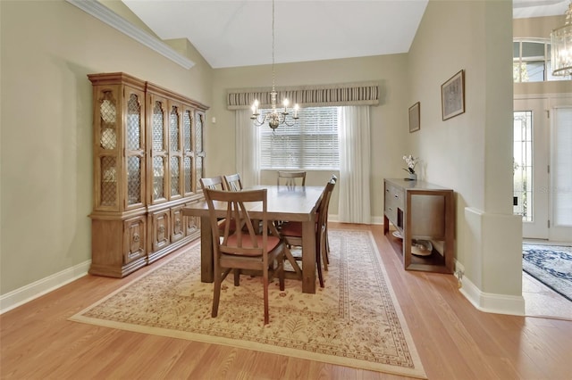 dining space featuring a chandelier, light hardwood / wood-style floors, and vaulted ceiling