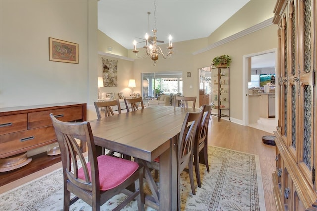 dining space with high vaulted ceiling, a chandelier, and light wood-type flooring