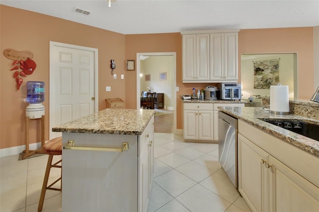 kitchen with light stone counters, sink, light tile patterned floors, dishwasher, and a center island