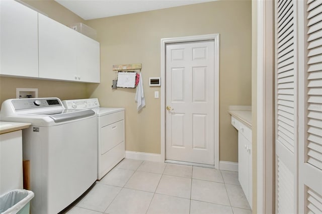 washroom with washer and clothes dryer, cabinets, and light tile patterned floors