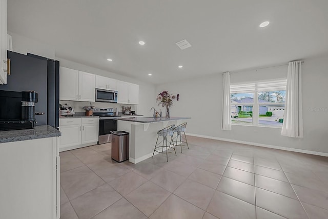 kitchen featuring white cabinetry, sink, stainless steel appliances, a kitchen island with sink, and light tile patterned flooring