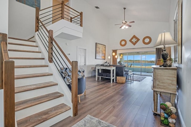 staircase featuring hardwood / wood-style floors, ceiling fan, and a high ceiling