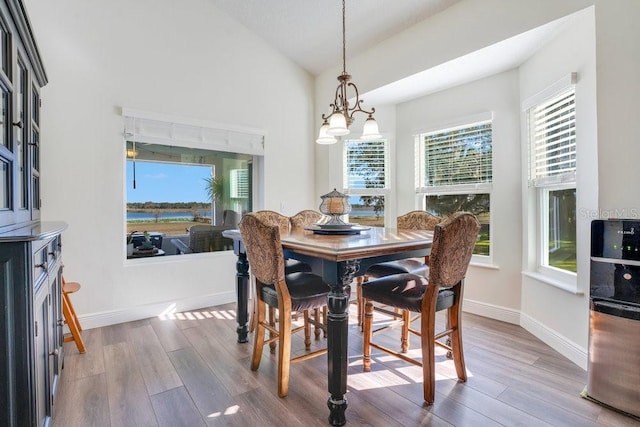 dining area featuring a chandelier, wood-type flooring, plenty of natural light, and lofted ceiling