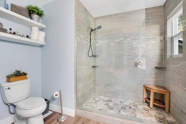 bathroom featuring toilet, wood-type flooring, and tiled shower