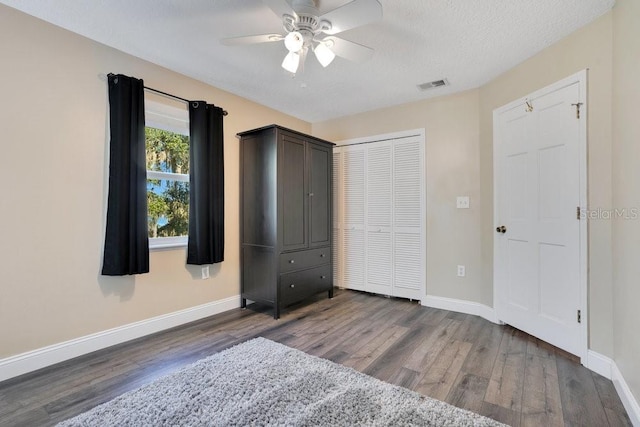 unfurnished bedroom featuring ceiling fan, dark hardwood / wood-style flooring, a textured ceiling, and a closet