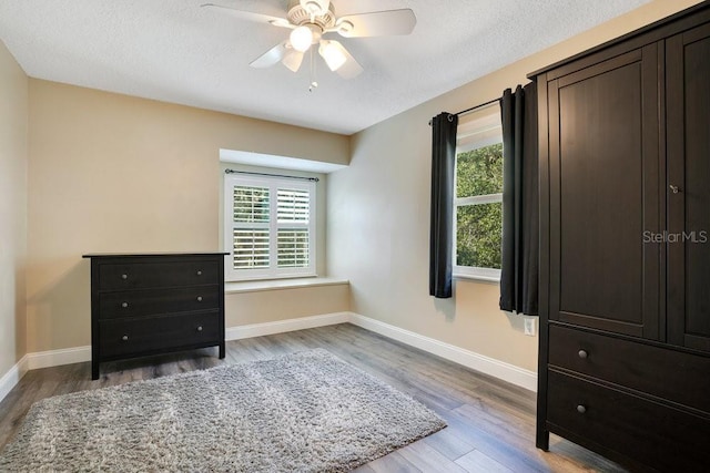 bedroom with ceiling fan, light hardwood / wood-style floors, and a textured ceiling