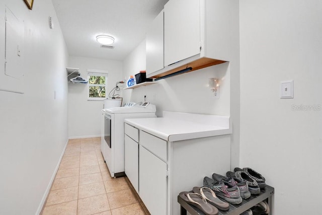 clothes washing area featuring cabinets, light tile patterned floors, and washing machine and clothes dryer