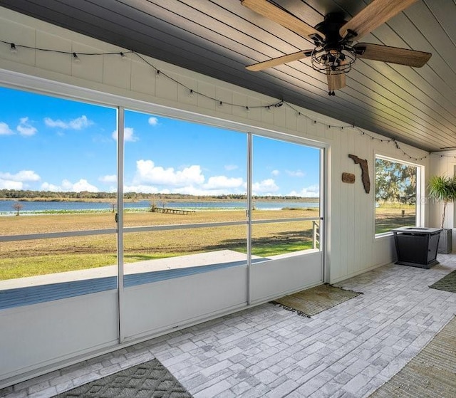 unfurnished sunroom with a water view and ceiling fan