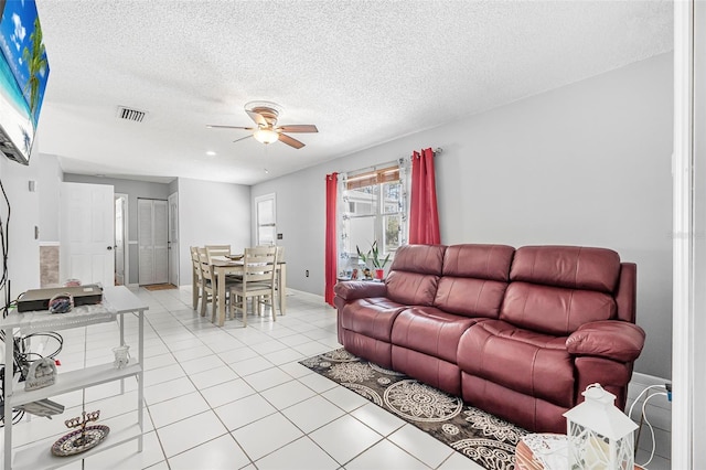 living room featuring light tile patterned floors, a textured ceiling, and ceiling fan