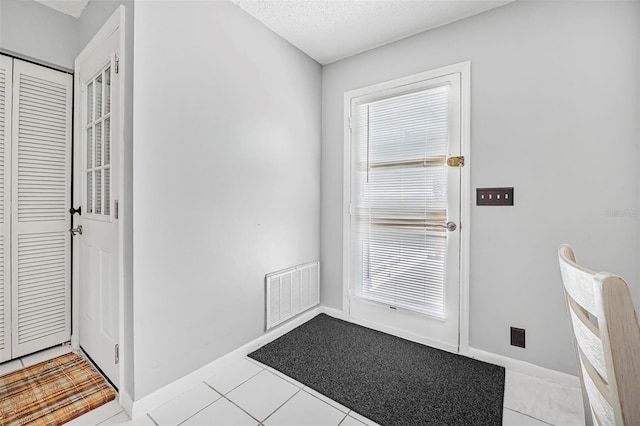 doorway with light tile patterned floors and a textured ceiling