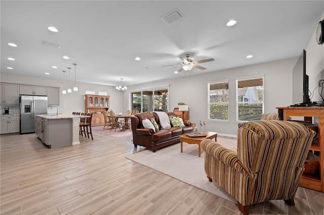 living room with plenty of natural light, ceiling fan with notable chandelier, and sink