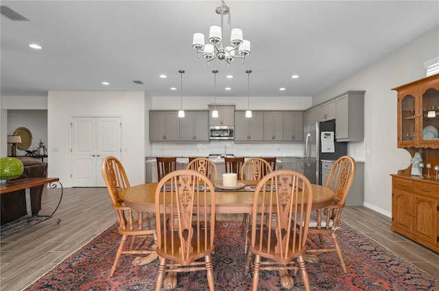 dining area featuring wood-type flooring and an inviting chandelier