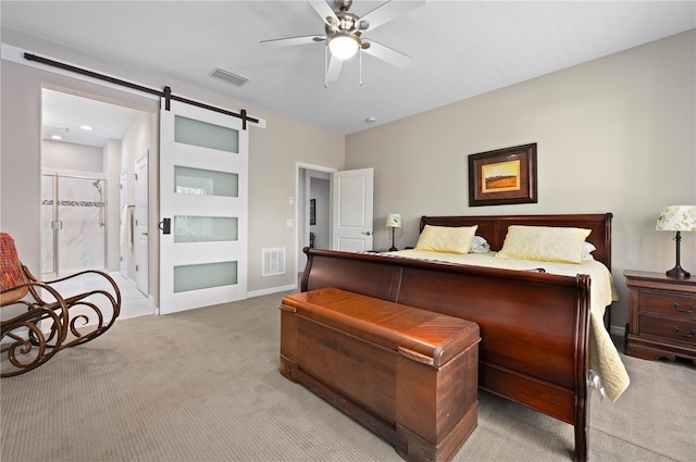 bedroom with ceiling fan, a barn door, light colored carpet, and ensuite bathroom