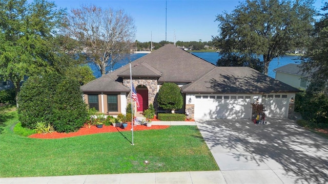 view of front of property with a front lawn, a water view, and a garage