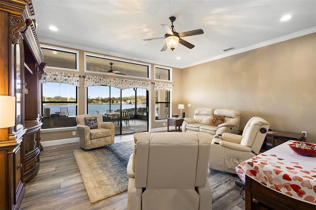 living room with hardwood / wood-style flooring, ceiling fan, a water view, and crown molding