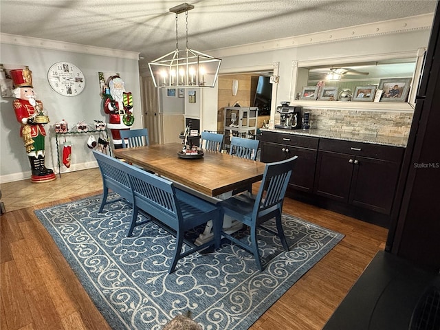 dining area with a textured ceiling, wood-type flooring, and ceiling fan with notable chandelier